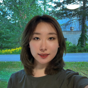 Susan poses outside while wearing an olive green t shirt