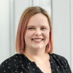 Sarah Morrison-Smith is a white woman with blonde and pink hair wearing a black button down shirt